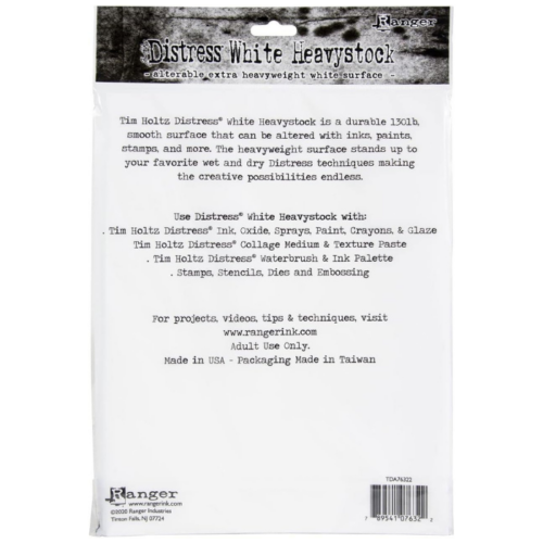 A single pack of Tim Holtz Distress Heavystock White is shown in the center of the frame, vertically. The image shows the back side of the pack. The pack is white plastic with a printed header that has the Distress logo and product name printed on it. There is black text on the white plastic packaging, describing the product. The image is center of the frame and on a white background.