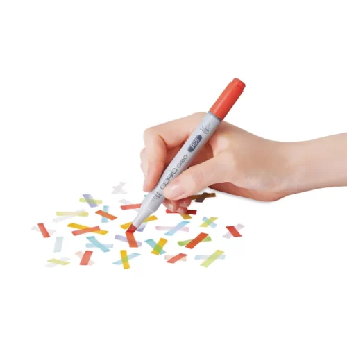 a person is using a copic ciao marker and drawing coloured lines across a bit of white paper. they are holding a red copic marker. the background is white.