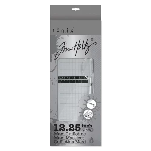 The Tim Holtz Maxi Guillotine Comfort Paper Trimmer is shown in it's cardboard box in the center of the frame vertically. The box is grey with black text and has a hang tab. On a white background.