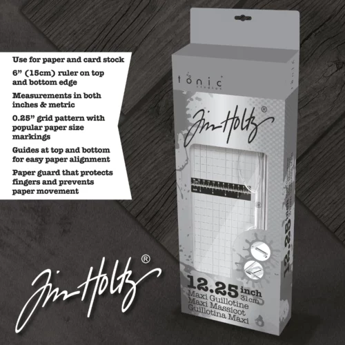 A promotional image for the Tim Holtz Maxi Guillotine Comfort Paper Trimmer. The trimmer has a light grey plastic base and a guillotine arm with a black kushgrip handle for comfort. The Tim Holtz logo is shown in the image. On a dark grey background.