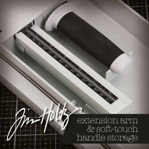 A promotional image for the Tim Holtz Maxi Guillotine Comfort Paper Trimmer. The trimmer has a light grey plastic base and a guillotine arm with a black kushgrip handle for comfort. The Tim Holtz logo is shown in the image. On a dark grey background.