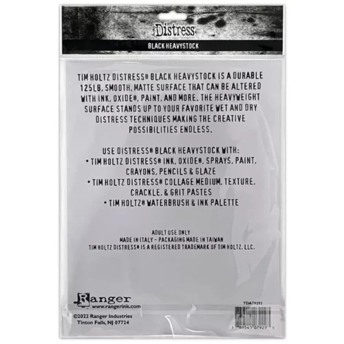 A single pack of Tim Holtz Distress Heavystock Black is shown in the center of the frame, vertically. The image shows the back side of the pack. The pack is white plastic with a printed header that has the Distress logo and product name printed on it. There is black text on the white plastic packaging, describing the product. The image is center of the frame and on a white background.