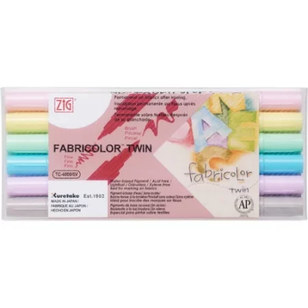 Fabricolor twin tip pastel set is sitting in the center of the image. the packaging is a pastel shade and the pens are lying horizontally in the case. the label in in the middle of the case. it is a pastel color with the name of the product written on it