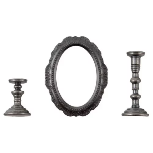 A close up of the contents of a pack of Tim Holtz Idea-ology The Manor. There are two metal candlesticks on either side of the frame and an oval metal frame in the center that is ornate. The candlesticks are also ornate. The candlestick on the left is smaller than the one on the right. The image is center of the frame and on a white background.