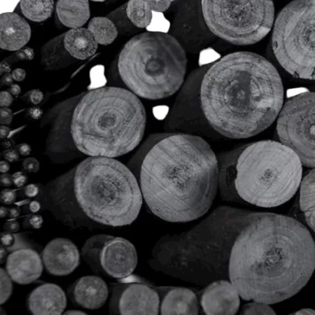 the image is full of the ends of the different sizes of charcoal sticks. they are round and black and dense sticks with a few white gaps in between them.
