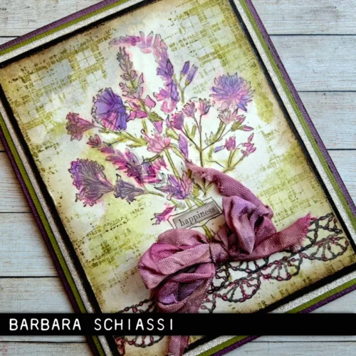 A card is shown in the frame, which was made using the Forgotten Garden Tim Holtz Stamp Set. The card is vintage and the flowers and bow are purple.
