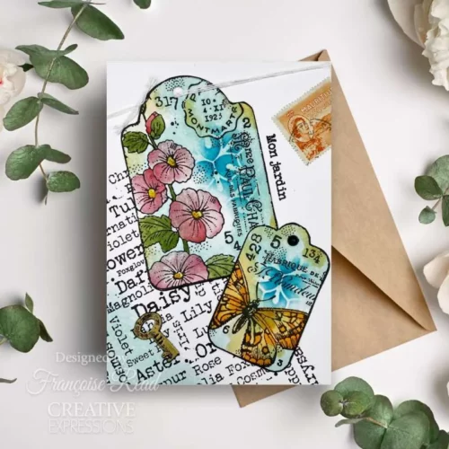 A Greeting Card that was made using the Garden Tags Woodware Clear Stamp Set is shown in the center of the frame. The stamp is printed in the background in black ink and a flower has been stamped over the top.