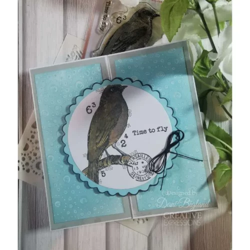 A card is shown in the frame that was made using the Kasbah Woodware Stencil. The background is blue and there is a stamped bird on the front.