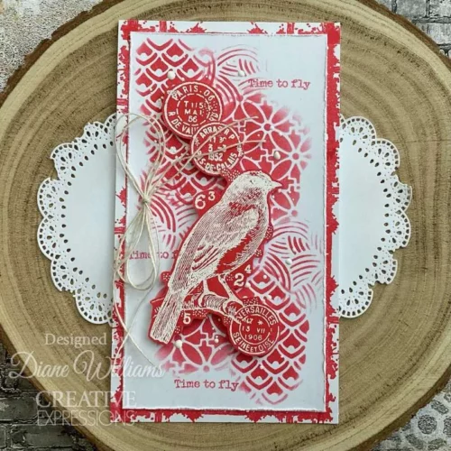 A card is shown in the frame that was made using the Organic Woodware Stencil. The background is white and red in the stencil design with a bird on the front of the card.