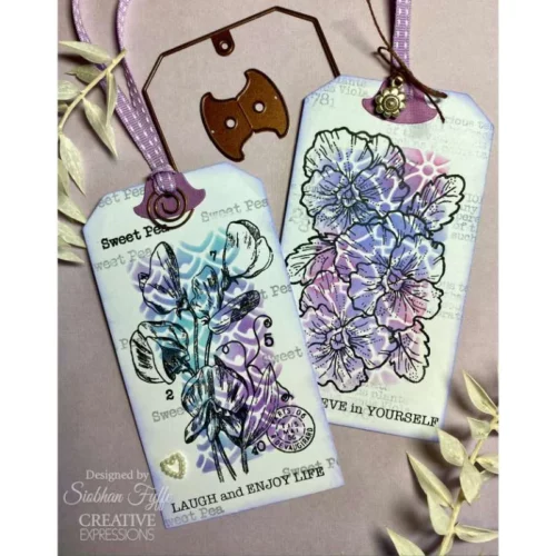 2 Tags are shown in the frame that were made using the Organic Woodware Stencil. The tags are purple and blue in colour and have the flowers stamped over the top with black.