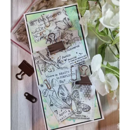 A greeting card that was made using the Spring Magnolia Woodware Clear Stamp Set is shown in the frame. The card is blue and green and the flowers have been stamped in black.