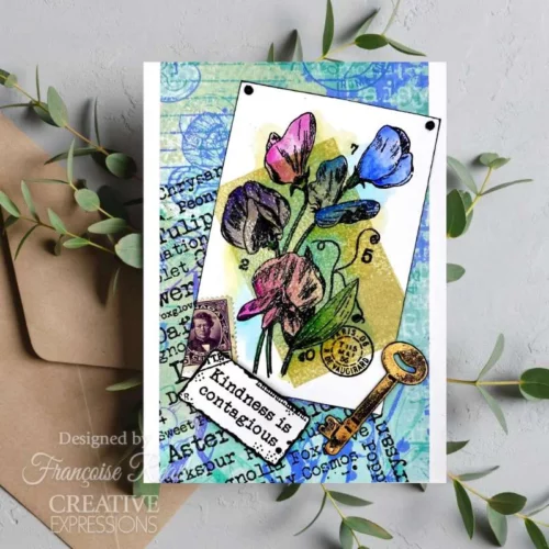 A Greeting Card is shown in the frame that was made using the Sweet Pea Woodware Clear Stamp Set. The card has a blue background and the flowers are stamped on top and coloured in.