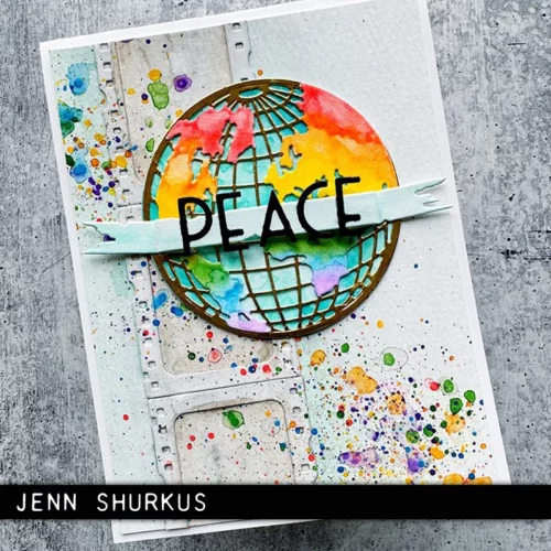 A greeting card was made using the Vault World Travel by Tim Holtz Thinlits Die Set and is shown in the frame. The card front has a world map on the front which is brightly coloured and the word 'peace'.