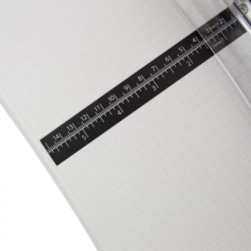 The Tim Holtz Rotary Media Trimmer has a light grey plastic base with grid marks debossed on the surface. It has a imperial and metric rulers with an extendable base and a geared rotary trimmer arm. In this frame, a close up of the the center line of the trimmer is shown. This is a black strip with imperial and metric markings on it.