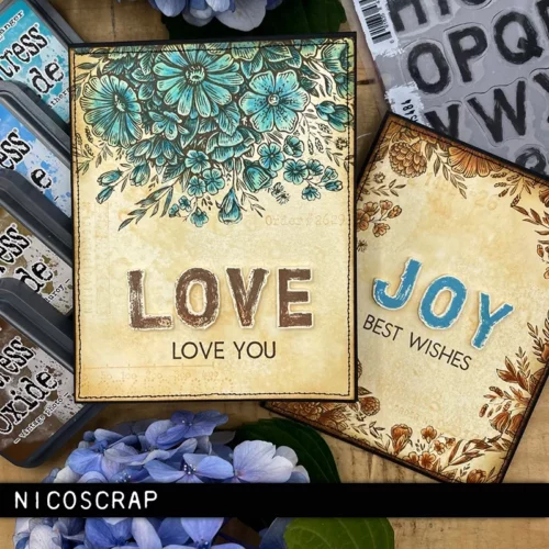 Two cards that were made using the Floristry Tim Holtz Stamp Set , are shown in the frame. They are brown with text and have flowers stamped on the covers. There are various ink pads scattered around the cards and the image is cut off by the frame.