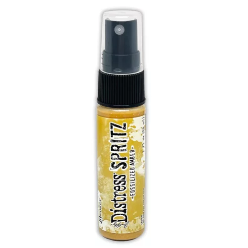 A single bottle of Fossilized Amber Tim Holtz Distress Spritz is shown standing vertically in the center of the frame. The bottle is a clear plastic with a black plastic spray top and a clear plastic lid. There is a coloured label around the body of the bottle that indicates the colour of the ink. The Distress Logo and product details are printed on the label. The image is center of the frame and on a white background.