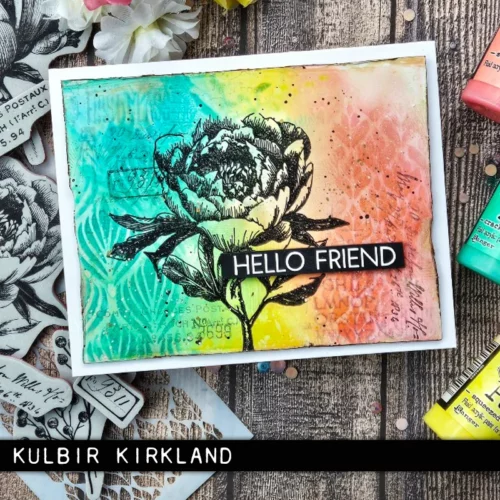 A single card is shown in the frame that was made using the French Garden Tim Holtz Stamp Set. The background is rainbow coloured and there is a large black flower stamped on top of the background with a sentiment that reads 'hello friend'. The image is cut off by the frame.