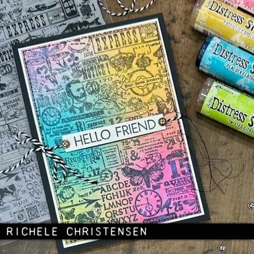 A single card that was made using the Hodgepodge Tim Holtz Stamp Set is shown in the frame. The card has the stamped imagery in the background and has been inked over the top with a rainbow of colours making it bright. There is a sentiment on the front of the card. There are a few Tim Holtz spritzes in the top right hand corner of the frame. The image is cut off by the frame.