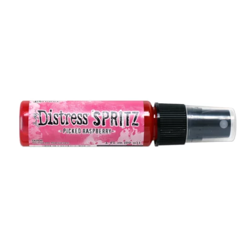 A single bottle of Picked Raspberry Tim Holtz Distress Spritz is shown laying horizontally in the center of the frame. The bottle is a clear plastic with a black plastic spray top and a clear plastic lid. There is a coloured label around the body of the bottle that indicates the colour of the ink. The Distress Logo and product details are printed on the label. The image is center of the frame and on a white background.