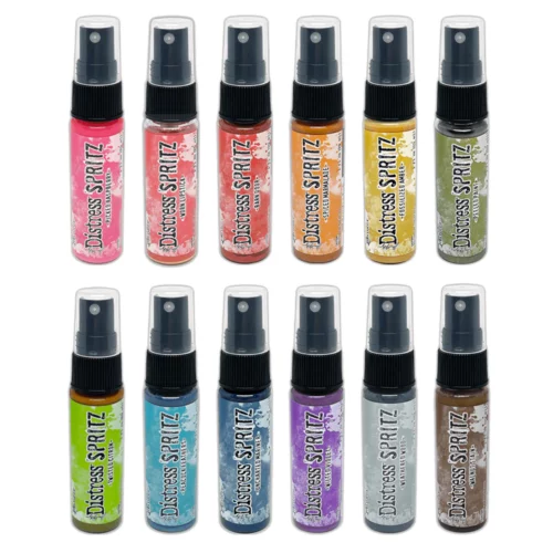 There are 12 bottles of Tim Holtz Distress Spritz shown in the frame. There are 2 rows and 6 bottles in each row. The bottles are a clear plastic with a black plastic spray top and a clear plastic lid. There is a coloured label around the body of each bottle that indicates the colour of the ink. The Distress Logo and product details are printed on the label. The image is center of the frame and on a white background.