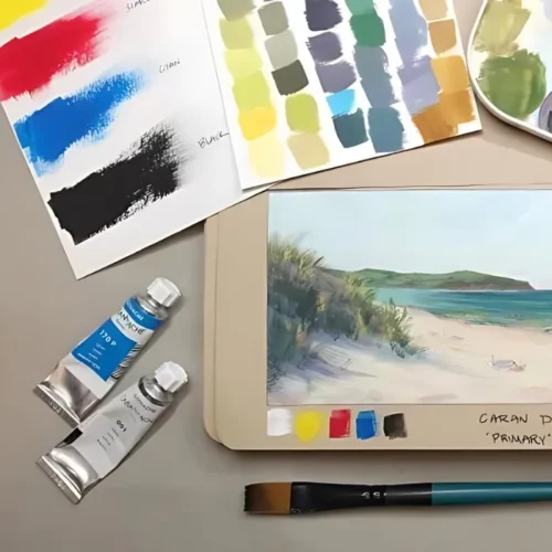 on the left of the image are two tubes of the paint lying next to a painting of an ocean scene. under the painting is a paintbrush and above is a colour swatch chart. all on a table top surface