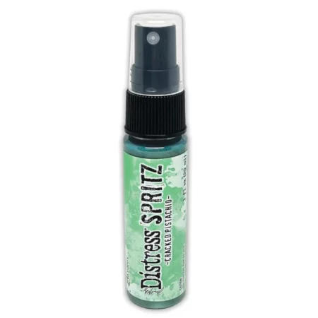 A single bottle of Cracked Pistachio Tim Holtz Distress Spritz is shown standing vertically in the center of the frame. The bottle is a clear plastic with a black plastic spray top and a clear plastic lid. There is a coloured label around the body of the bottle that indicates the colour of the ink. The Distress Logo and product details are printed on the label. The image is center of the frame and on a white background.