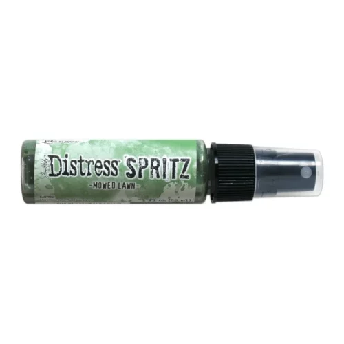 A single bottle of Mowed Lawn Tim Holtz Distress Spritz is shown laying horizontally in the center of the frame. The bottle is a clear plastic with a black plastic spray top and a clear plastic lid. There is a coloured label around the body of the bottle that indicates the colour of the ink. The Distress Logo and product details are printed on the label. The image is center of the frame and on a white background.