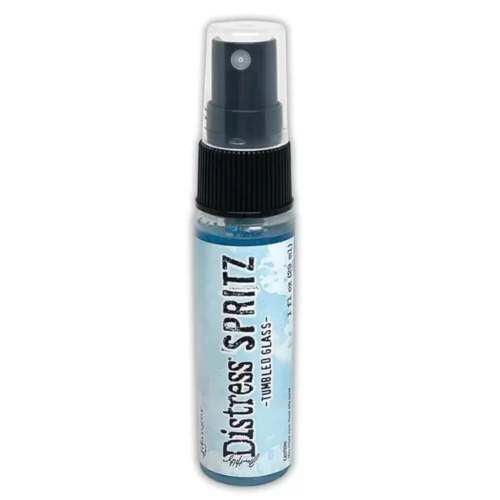 A single bottle of Tumbled Glass Tim Holtz Distress Spritz is shown standing vertically in the center of the frame. The bottle is a clear plastic with a black plastic spray top and a clear plastic lid. There is a coloured label around the body of the bottle that indicates the colour of the ink. The Distress Logo and product details are printed on the label. The image is center of the frame and on a white background.