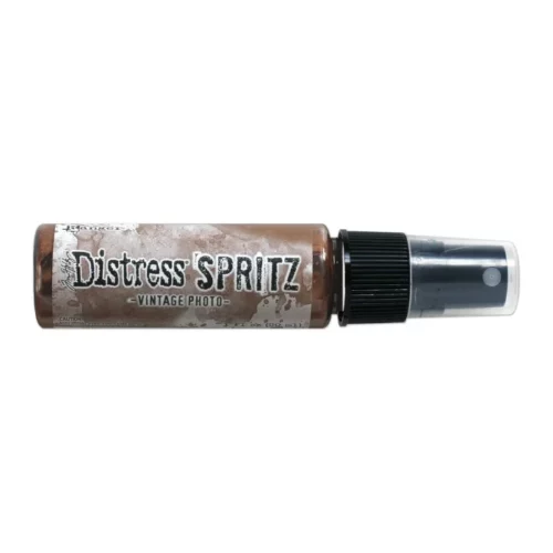 A single bottle of Vintage Photo Tim Holtz Distress Spritz is shown laying horizontally in the center of the frame. The bottle is a clear plastic with a black plastic spray top and a clear plastic lid. There is a coloured label around the body of the bottle that indicates the colour of the ink. The Distress Logo and product details are printed on the label. The image is center of the frame and on a white background.